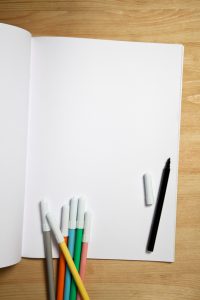 Notebook and color pens on table.